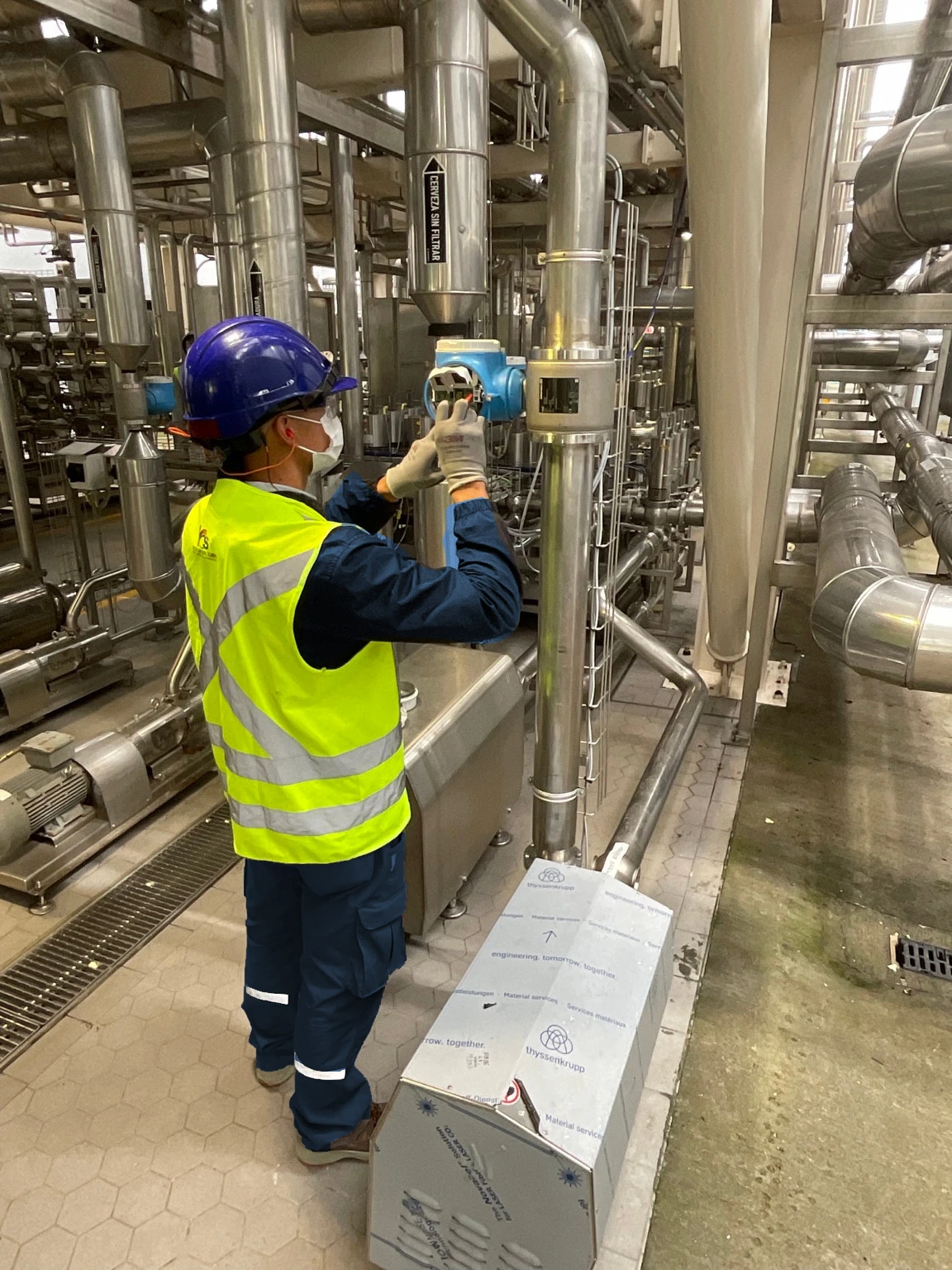 Técnico con dotación ICS junto a tuberías y un instrumento industrial