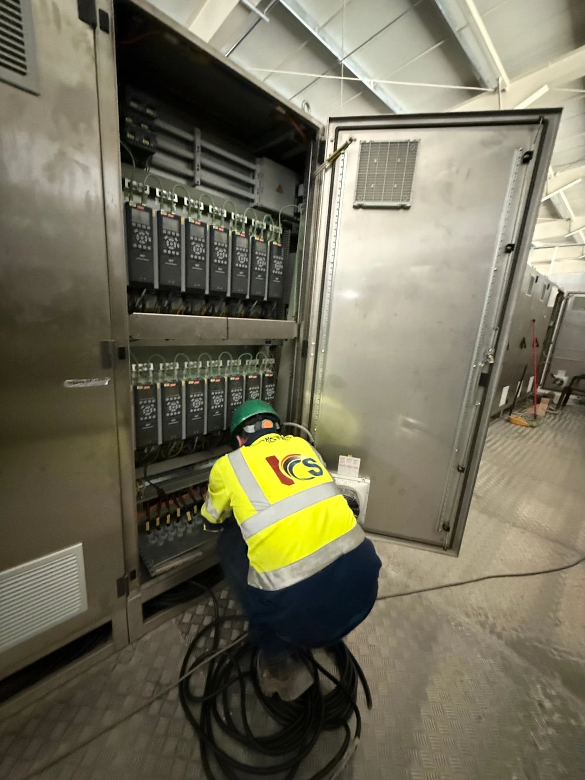 Techniker in ICS-Arbeitskleidung an einem industriellen Schaltschrank